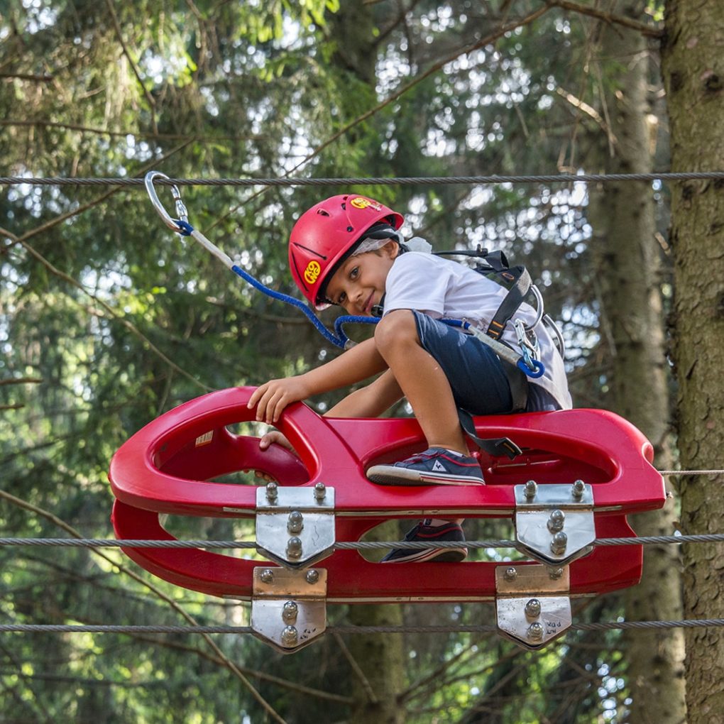 Passaggio con slittino nel percorso per bambini tra gli alberi del parco divertimenti