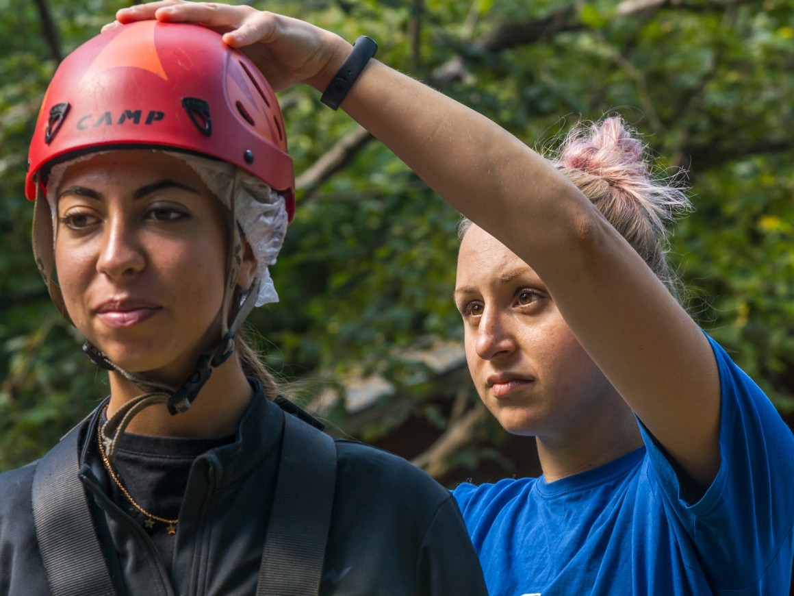 Istruttrice aiuta ragazza ad indossare il casco