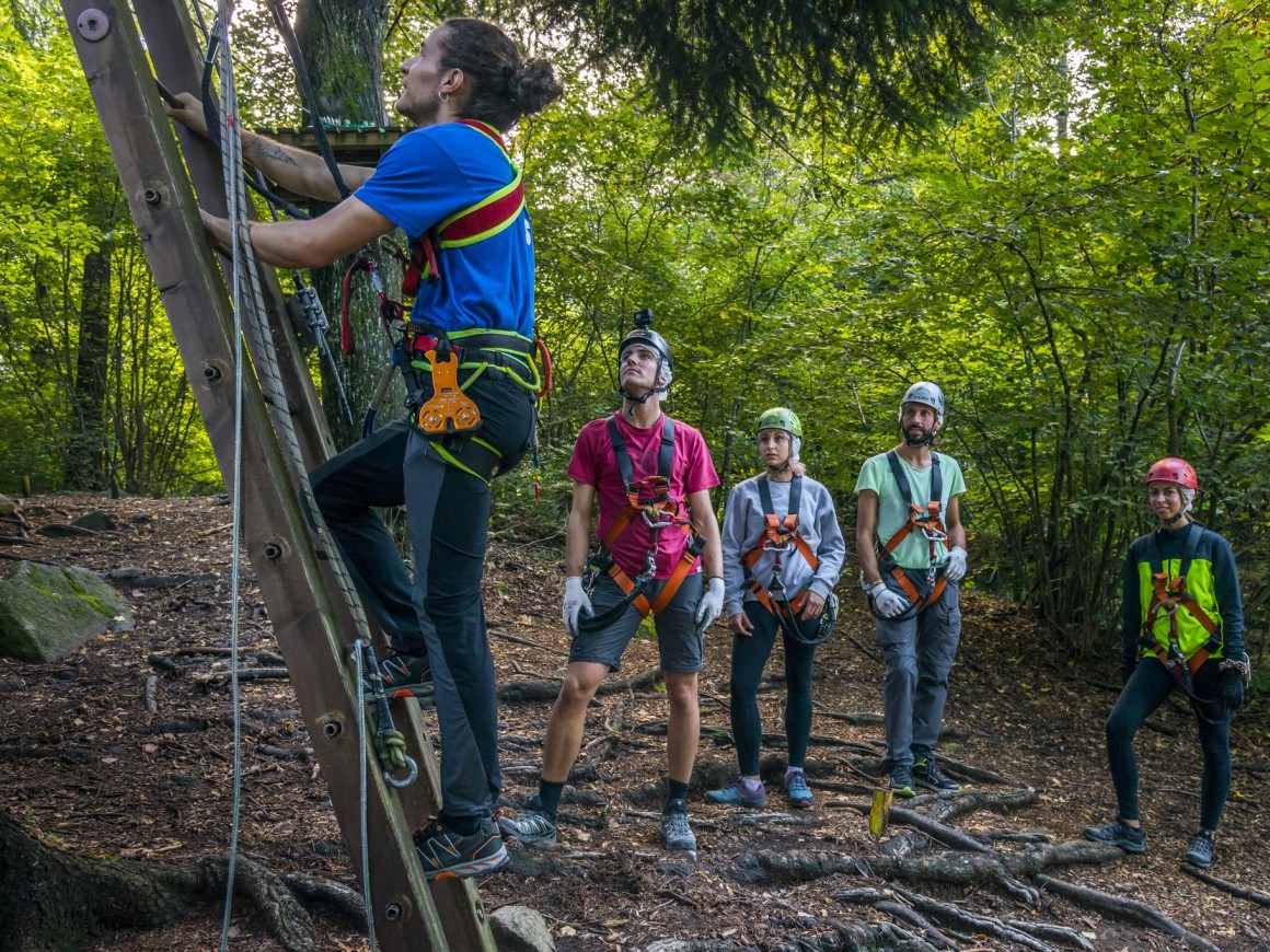 Istruttore mostra al gruppo come salire sui percorsi avventura